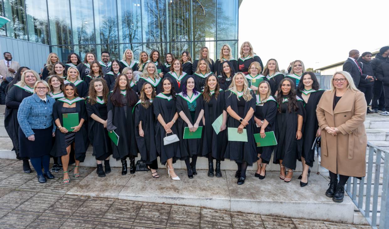 A large group of nursing students wearing graduation gowns pose on the steps outside the Sports Centre alongside NHS Forth Valley’s Executive Nurse Director Professor Frances Dodd and Director of Nursing Professor Karen Goudie